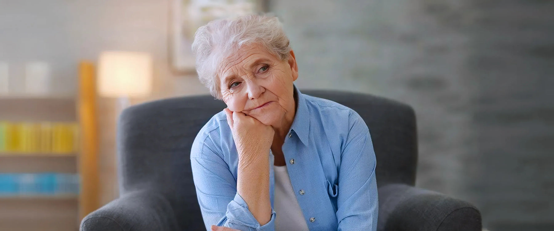 Depressed elderly woman sitting in arm-char at home