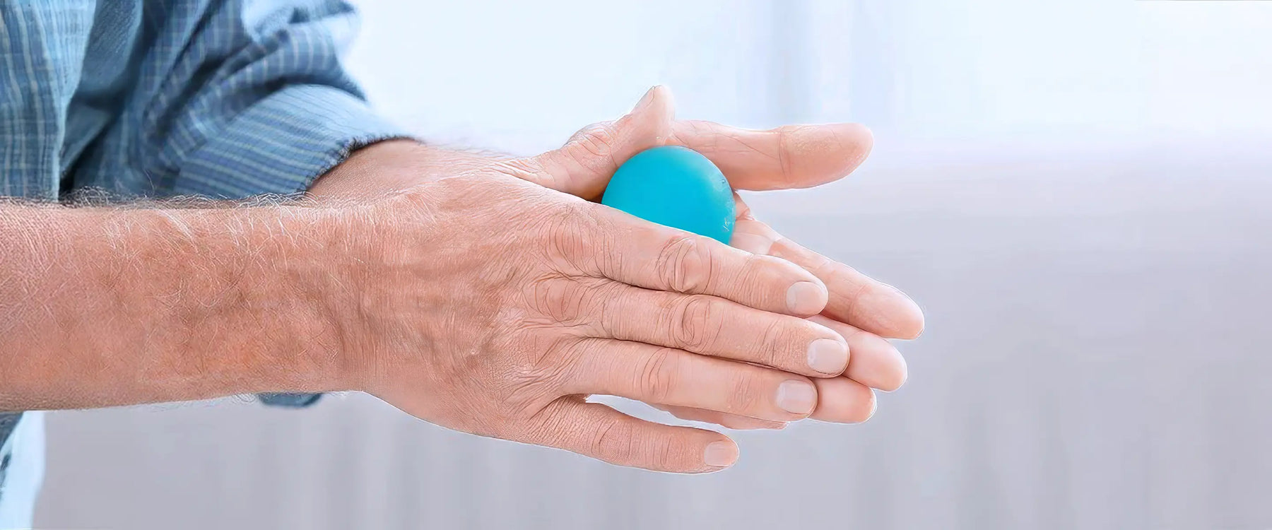Hands of senior man doing exercise with rubber ball