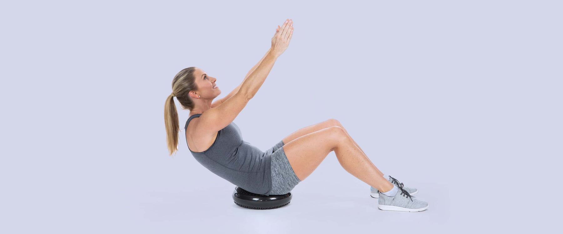 Woman doing a stretching pose on a wobble cushion