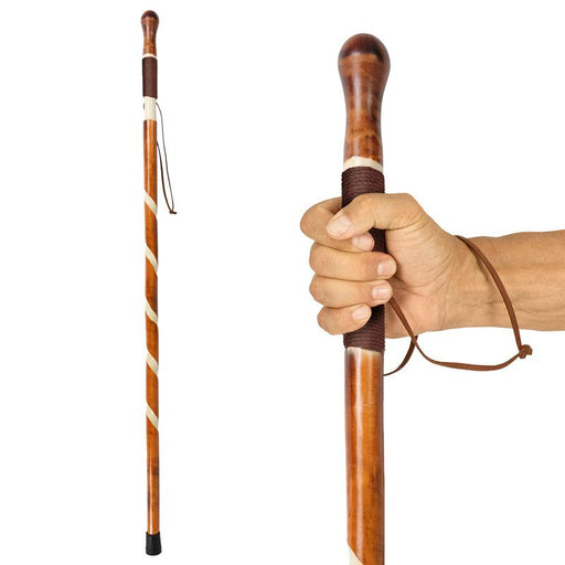 A hand holding a carved wooden walking stick with a rope handle and a non-slip rubber tip.